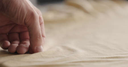 man touching yellow cotton clothes closeupの写真素材