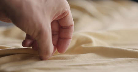 man touching yellow cotton clothes closeupの写真素材