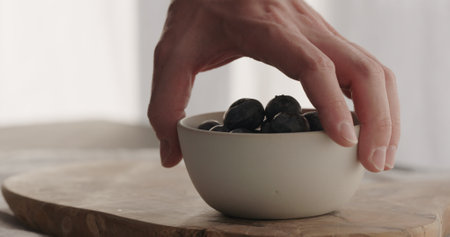 man put fresh blueberries in blue bowl on linen clothの写真素材