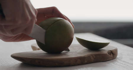 man cut ripe mango on olive wood boardの写真素材
