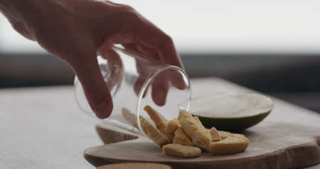 man pour freeze dried mango from glass jar on olive wood boardの写真素材