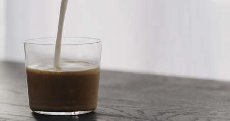 making cappuccino in tumbler glass on black aok tableの写真素材
