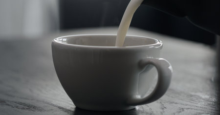 pour steamed milk into white cup making cappuccino with copy spaceの写真素材