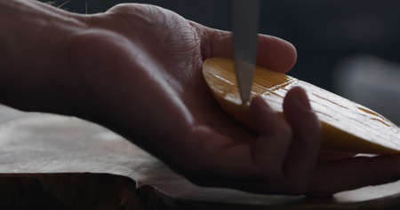 man cut thailand mango on olive board closeup