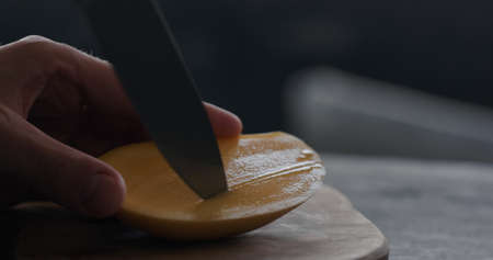 man cut thailand mango on olive board closeup
