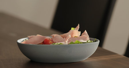 prosciutto cotto on greens in blue bowl on walnut table making saladの写真素材