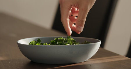 put kale in blue bowl on walnut table making saladの写真素材