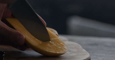 man cut thailand mango on olive board closeupの写真素材