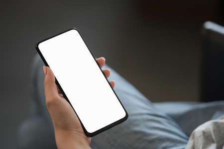 Young woman hold smarphone with white screen while sitting in a chair