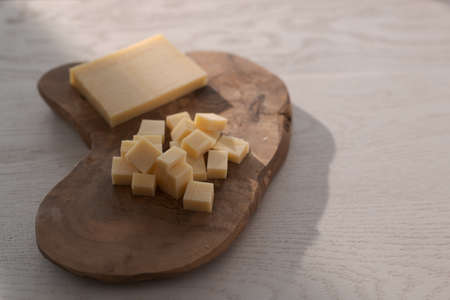 Small block of aged cheese sliced in small pieces on wood boardの写真素材