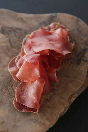 bresaola slices on olive wood boardの写真素材