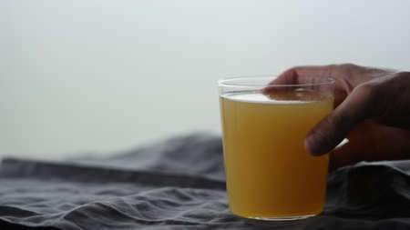 man hand take orange soft drink in tumbler glass from linen cloth