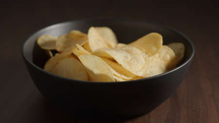 potato chips in black bowl on wood tableの写真素材