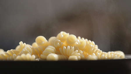 fusilli on black plate with steam risingの写真素材