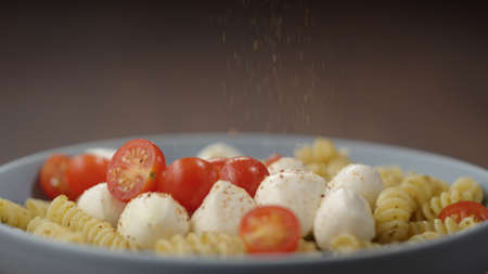 spices fall on pesto fusilli in blue bowl