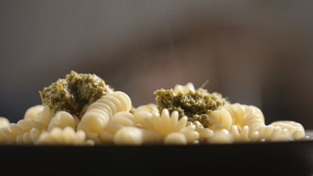 add pesto sauce to fusilli on black plateの写真素材