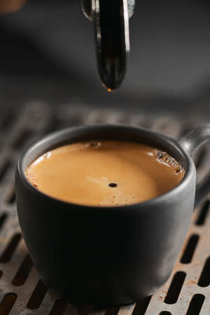 Closeup espresso last drop with single spout portafilter in black cupの写真素材
