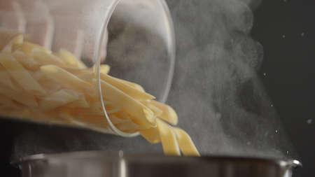 dry penne rigate poured in saucepan with boling water
