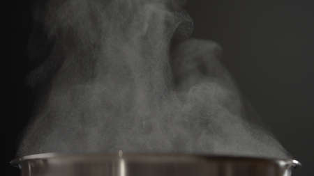 closeup shot of steam rising from steel saucepan on stoveの写真素材