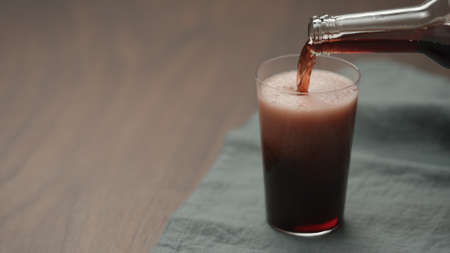 pour dark berry drink in tumbler glass on walnut table with copy spaceの写真素材