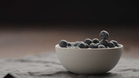 ripe blueberries in white bowl on walnut tableの写真素材