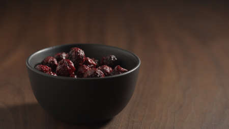 freeze-dried cranberries in black bowl on wood table with copy spaceの写真素材