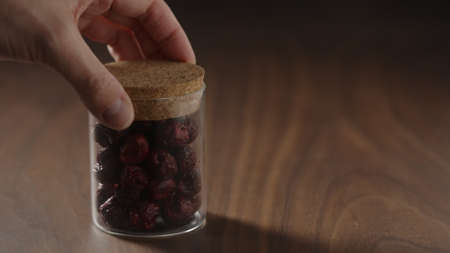 man put freeze-dried cranberries in glass can on wood tableの写真素材