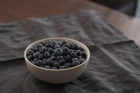 Blueberries in ceramic bowl on wood tableの写真素材