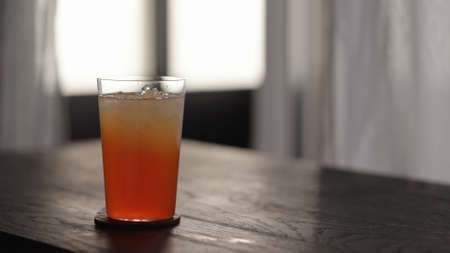 orange syrup in lemonade in tumbler glass with crushed ice on wood tableの写真素材
