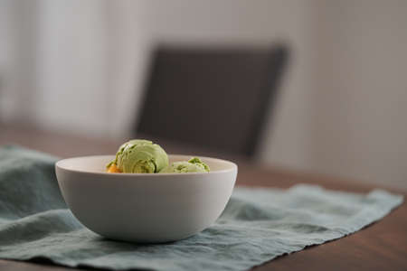 green matcha tea ice cream with fresh mango in white bowlの写真素材