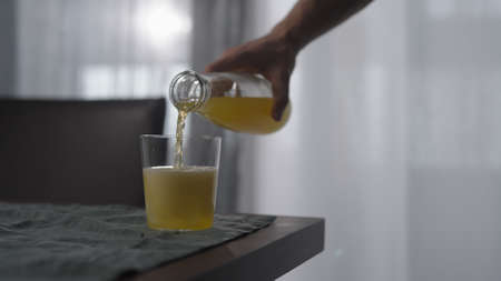 man pour lemonade in tumbler glass with ice cube on wood tableの写真素材
