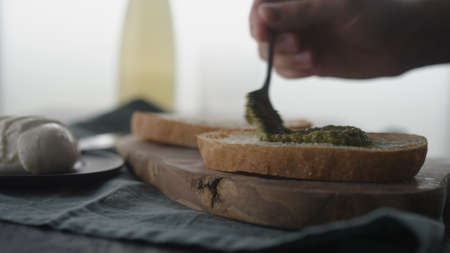 Man spreading pesto on ciabatta slice