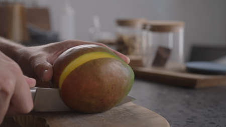 Man cutting fresh mango on wood boardの写真素材