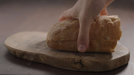 man put sliced in halves ciabatta on olive wood boardの写真素材