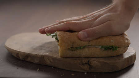 man making sandwich, add top ciabatta on olive wood boardの写真素材