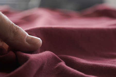 man hand touching red wine color cotton fabricの写真素材