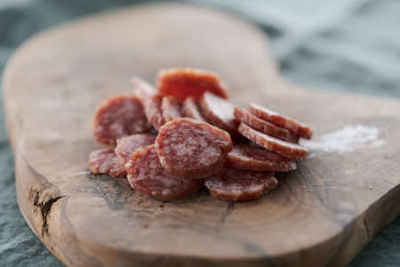 Sliced cured sausage on olive serving boardの写真素材