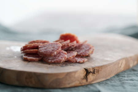Sliced cured sausage on olive serving boardの写真素材