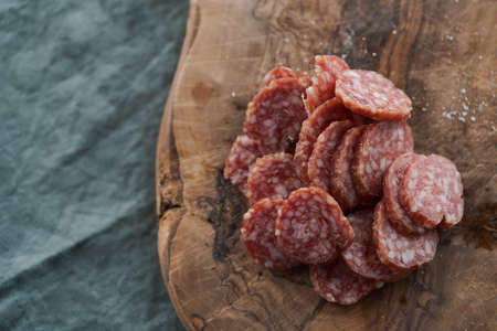 Sliced cured sausage on olive serving boardの写真素材