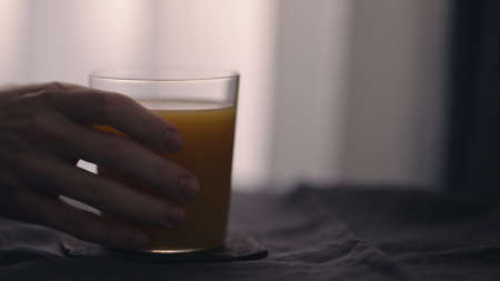 man take orange mango juice in tumbler glass on linen clothの写真素材