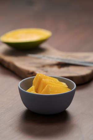 Fresh sliced mango in a ceramic bowl on walnut tableの写真素材