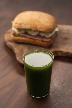Green matcha drink in tumbler glass with sandwich on backgroundの写真素材