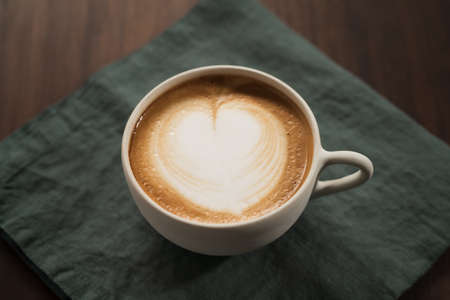 Fresh flat white with latte art in ceramic cup on wood tableの写真素材