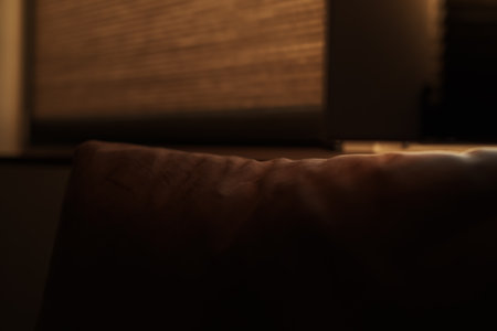 Closeup shot of couch pillow with window on background with sunset lightの写真素材