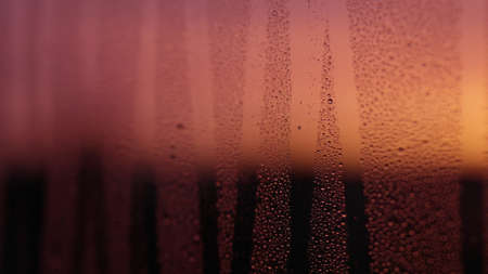 Water drops on window glass with sunset lightの写真素材