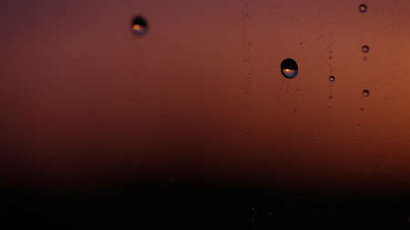 Water drops on window glass with sunset light