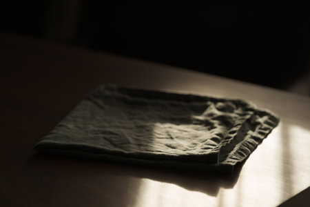 green linen napkin on walnut wood table with sunset lightの写真素材