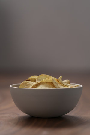 Organic potato chips with black pepper in white bowl on wood tableの写真素材