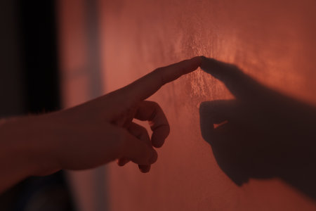 Abstract man hand touch wall with sunset light and long shadows