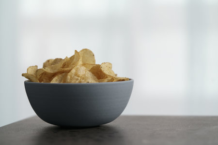 Organic potato chips with black pepper in blue bowl on counterttopの写真素材